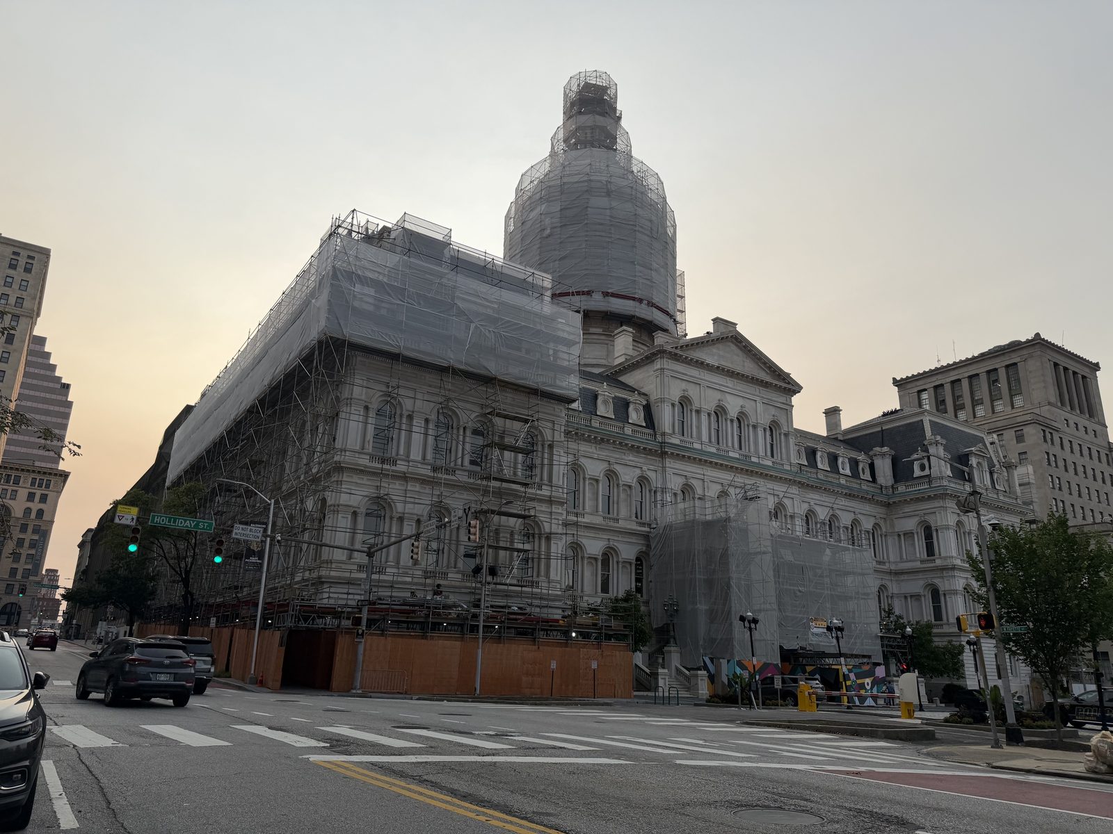 Large municipal building covered in scaffolding and protective wrap